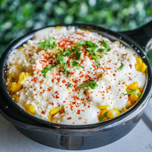 Crush Taco's elote, a Mexican street corn dish, topped with white cheese, red chili flakes, and cilantro.
