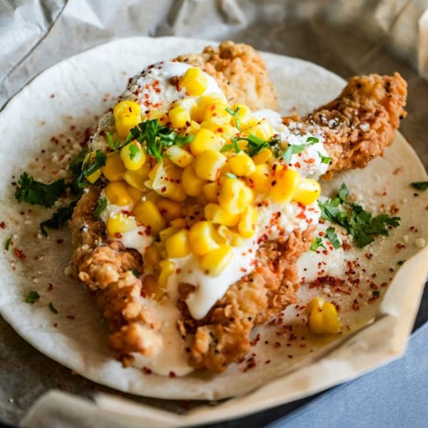 Crush Taco's fried chicken taco with corn salsa, crema, and cilantro on a tortilla.