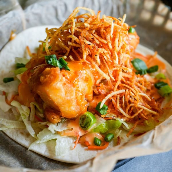 A Crush Taco with crispy fried shrimp, shredded lettuce, sauce, and crispy potato strings.