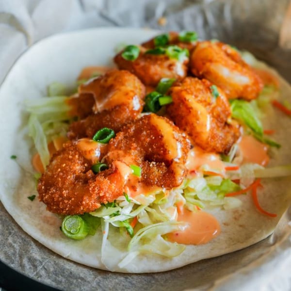 Crush Taco's crispy shrimp taco with shredded lettuce, sauce, and green onions on a tortilla.