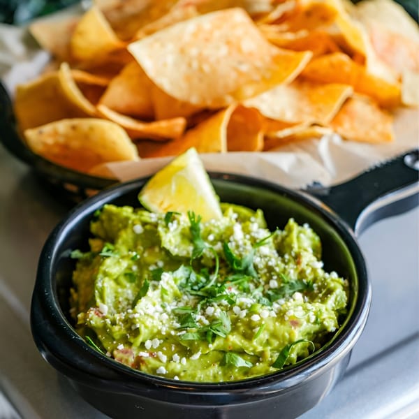 Crush Taco's guacamole with cotija cheese, cilantro, and a lime wedge, served with tortilla chips.